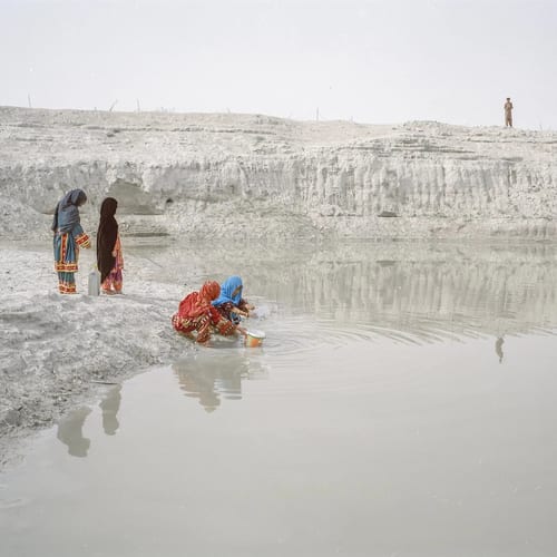 Choutani village, Dashtyari region, Cha’bahar, Balouchestan. Four girls from a family in Choutani village are taking water from a Houtag. “Houtags” are pits in which rain water has gathered; in Cha’bahar region, there are many Houtags, but during droughts their water is dirty and muddy. The livestock drink from this source of water and some of the families who are less well-off financially use this water to wash their clothes and do other daily chores. When they lack drinking water, they also have to take this dirty water, boil it, and use it. From the series 'An Elegy for the Death of Hamun' (2018), image © Hashem Shakeri