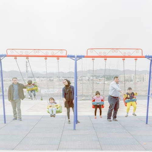 Parents pushing their children on swings in the only park in the city of Abshenasan.