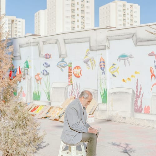 Maghsoud, 54, is trying to light his cigarette using a magnifier and the sunlight in the new city of Parand.